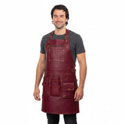 "Man wearing a burgundy leather apron with brass buckles and multiple tool pockets over a gray t-shirt."