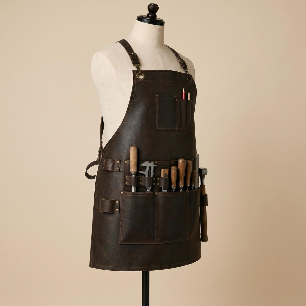Side front view of brown leather woodworking apron holding chisels, measuring tools, ruler and hammer in multiple utility pockets and loops.