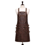 "Front view of a full-length dark brown leather apron displayed on a fabric mannequin, featuring adjustable neck straps with brass buckles, a zippered chest pocket, and multiple front pockets on the waist section with buckle straps and brass rivets, photographed against a plain white background."