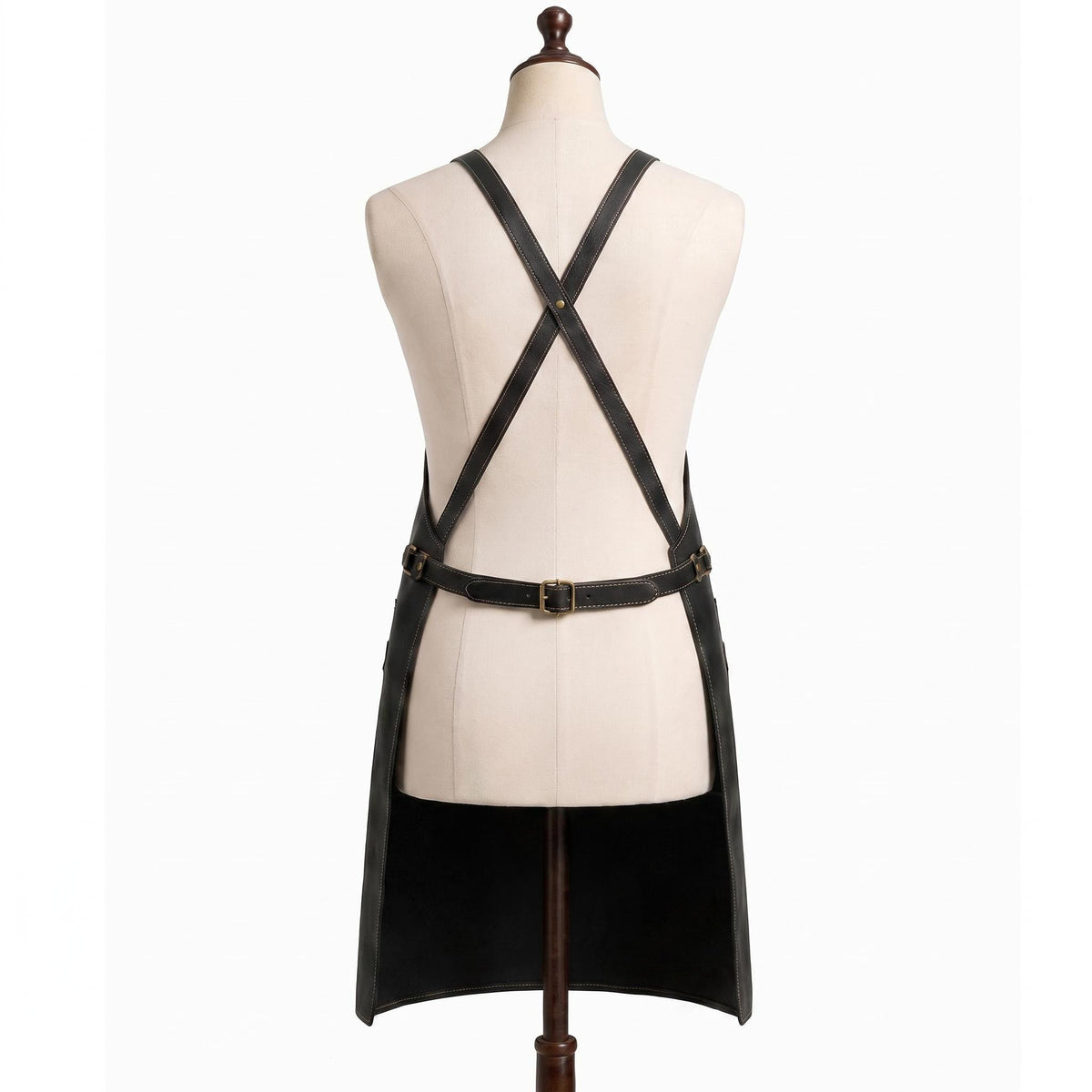 "Back view of black leather apron with crossback straps and adjustable brass buckle belt on a mannequin."