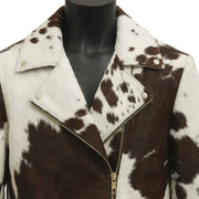 "Close-up view of the collar and zipper of a cowhide print leather biker jacket displayed on a black mannequin, featuring a gold zipper and studs, on a soft cream-colored background.")
