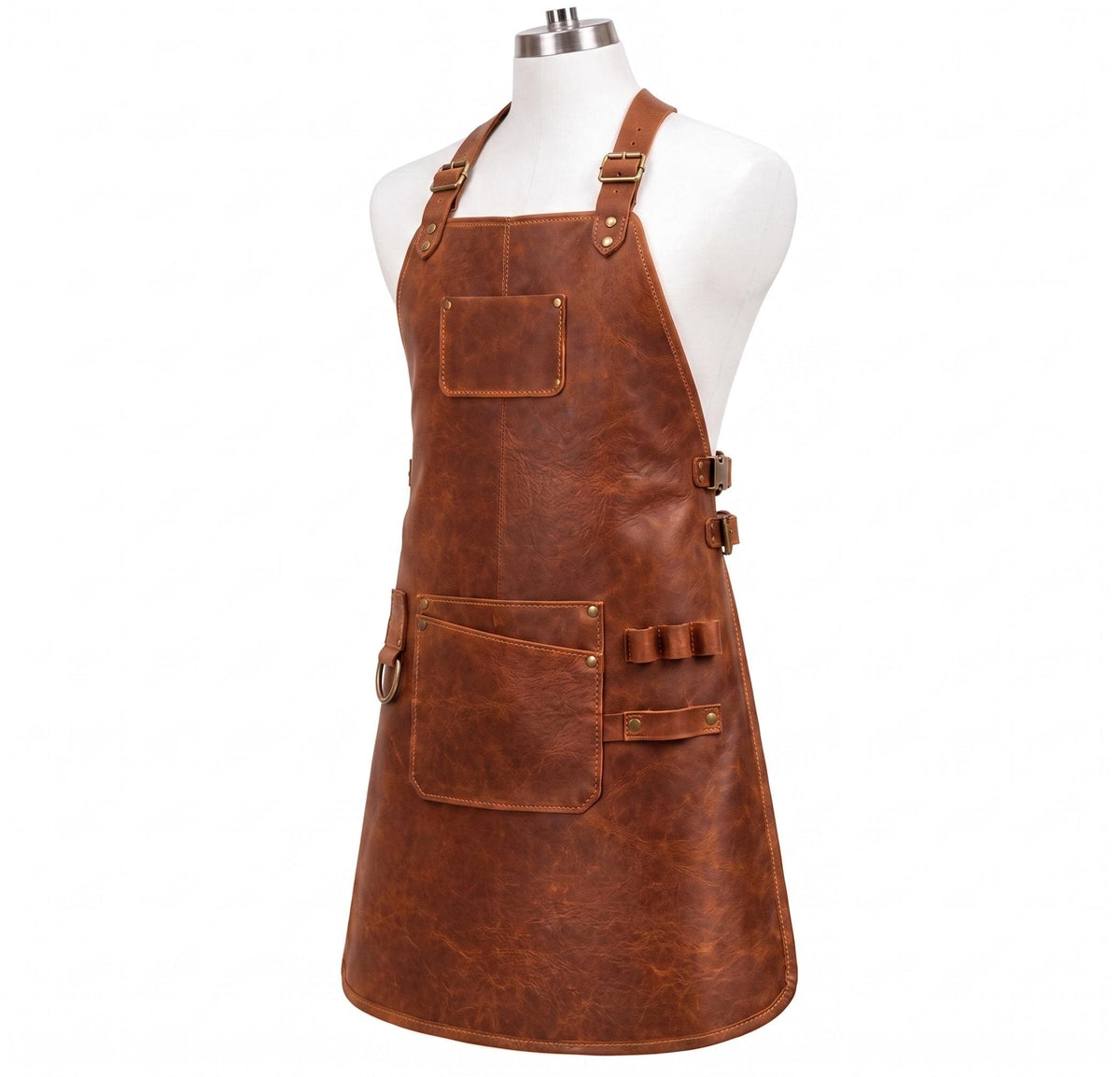 "Angled view of brown distressed leather work apron on mannequin, featuring adjustable brass-buckle neck strap, chest pocket, large front pocket, multi-loop tool holder strap, D-ring, and side buckle straps, against a white background."