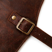 Macro close-up of leather apron brass buckle and adjustable waist strap showing hardware and stitching detail