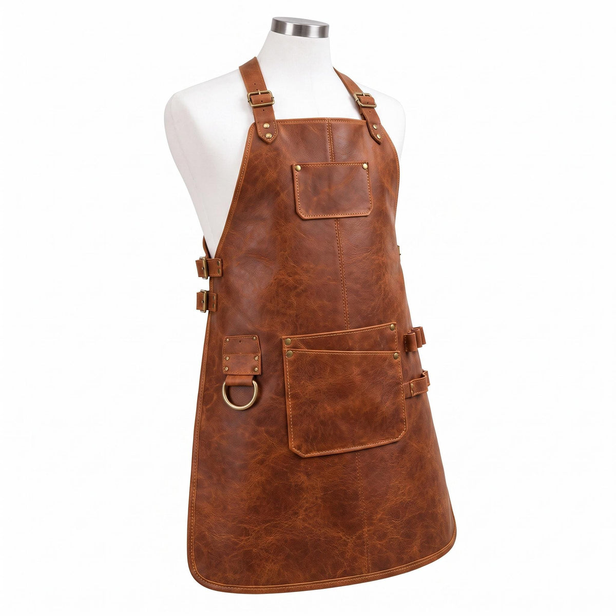 "Angled side view of brown distressed leather work apron on mannequin, showing adjustable neck strap with brass buckle, chest pocket, large front pocket with pen slot, tool loops, and D-ring, against a white background."