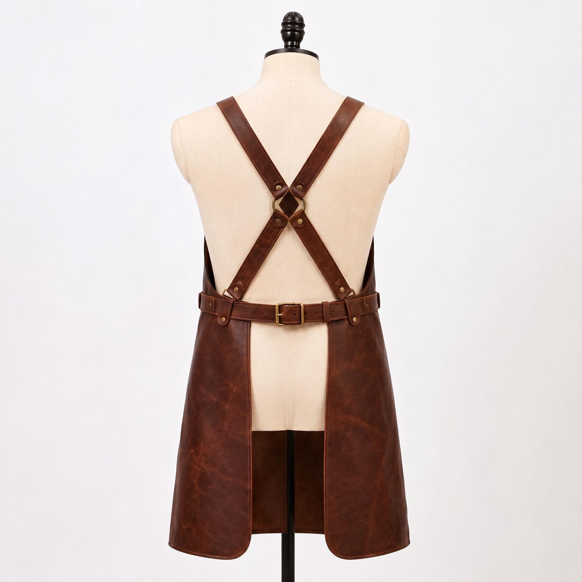 Back view of brown leather BBQ apron showing adjustable cross-back X straps, waist belt and brass hardware.