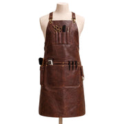"Distressed brown leather barber apron with tool pockets holding scissors, comb, clippers, and brush, styled on a mannequin."