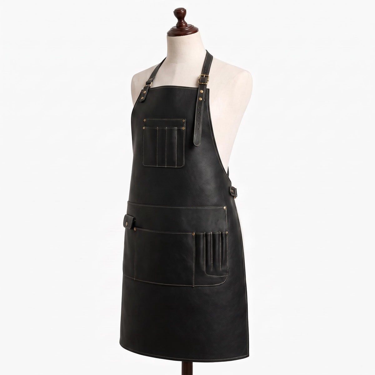 "Angled view of empty black leather apron showing chest pocket, lower pockets, and adjustable buckle straps.