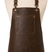 "Close-up of distressed brown leather apron's chest area showing brass grommets, adjustable neck straps with hooks, and a riveted front pocket with contrast stitching."