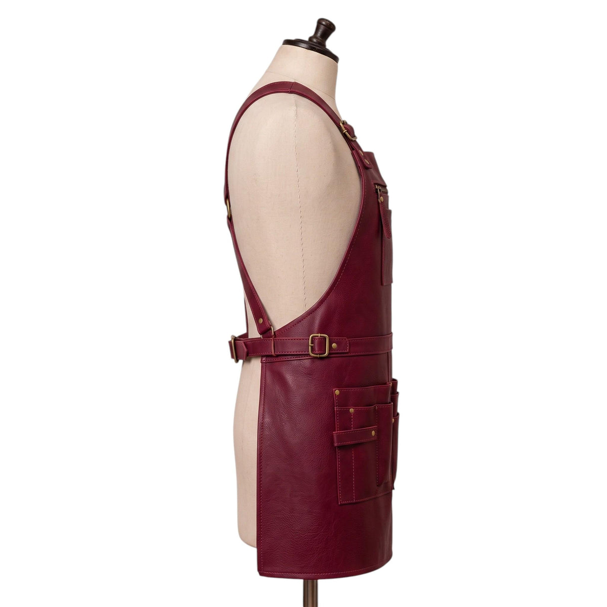 "Side profile view of a burgundy leather apron showing the neck buckle, waist belt, and lower tool pockets from the other side."