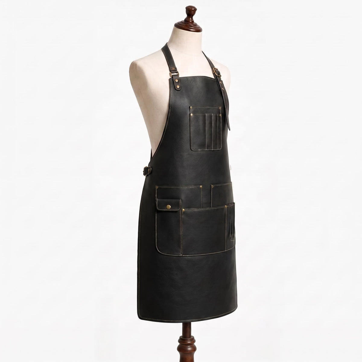 "Side view of black leather apron showing chest pocket and multiple lower storage pockets with brass buckle straps."