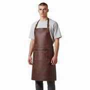 "Man wearing a brown leather apron over a gray t-shirt, standing against a white background."