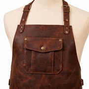 Close-up of leather apron chest pocket with brass snap button and adjustable neck strap buckles on mannequin