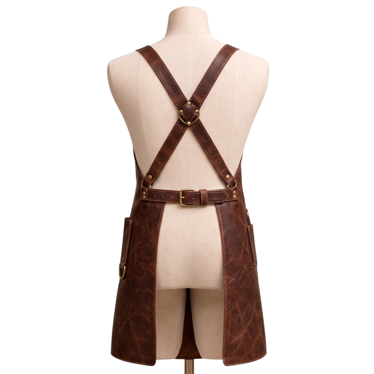 "Rear view of brown leather barber apron showing crossback straps and adjustable buckle belt on a mannequin."