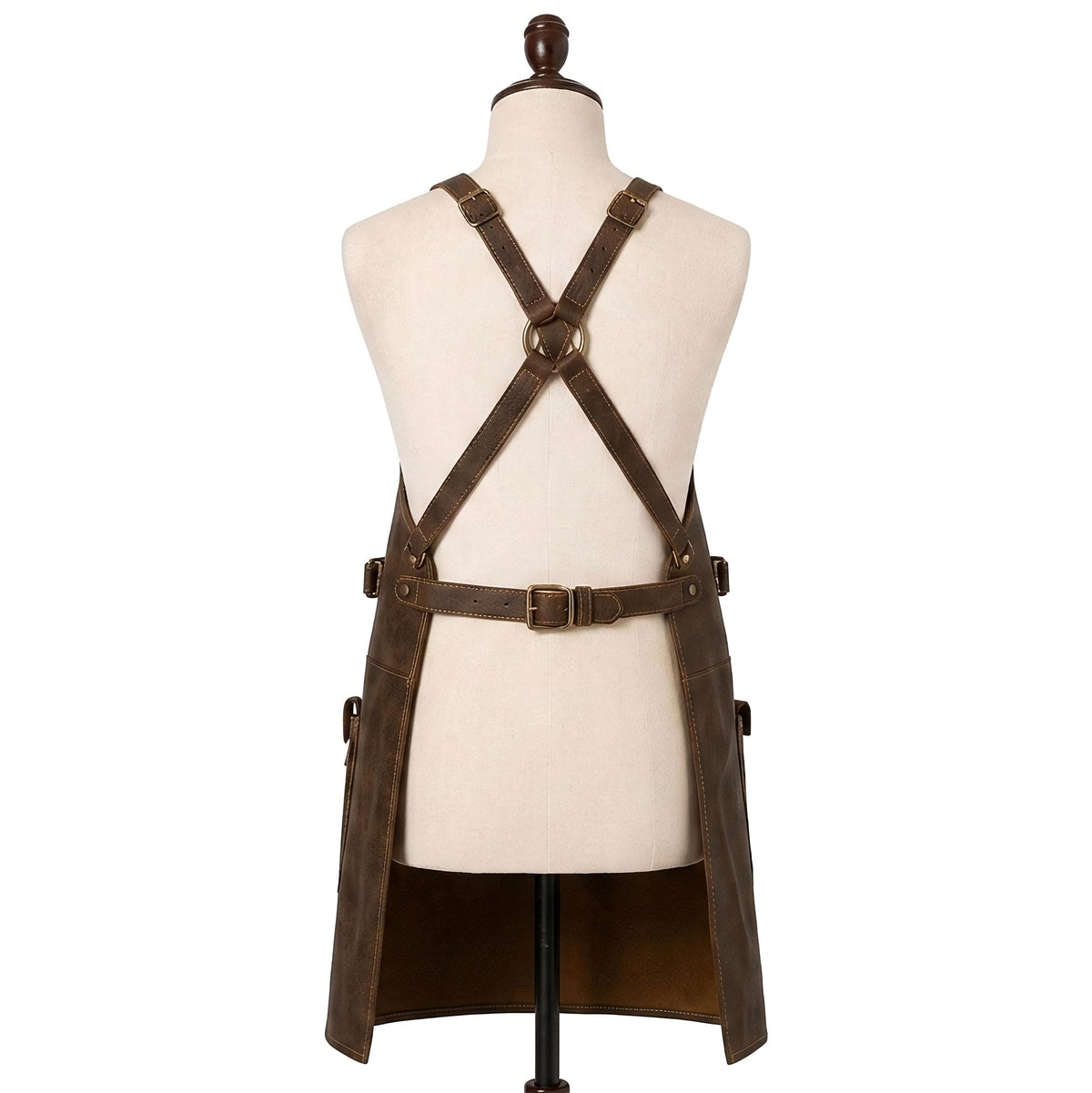 "Back view of distressed brown leather apron on a mannequin, showing crisscross X-back straps with brass buckles and an adjustable waist belt, against a white background."