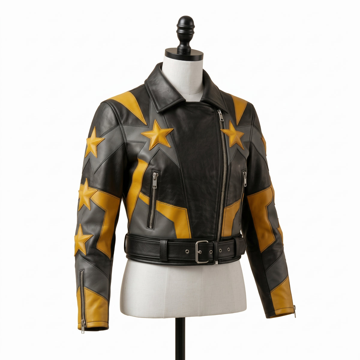 "Angled view of a black leather biker jacket with yellow and gray star graphic panels, asymmetric front zipper, zip pockets, and belted waist, displayed on a mannequin against a white background."