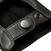 "Extreme close-up of the wrist snap-button closure on a black leather driving glove, showing the leather texture and soft interior lining."