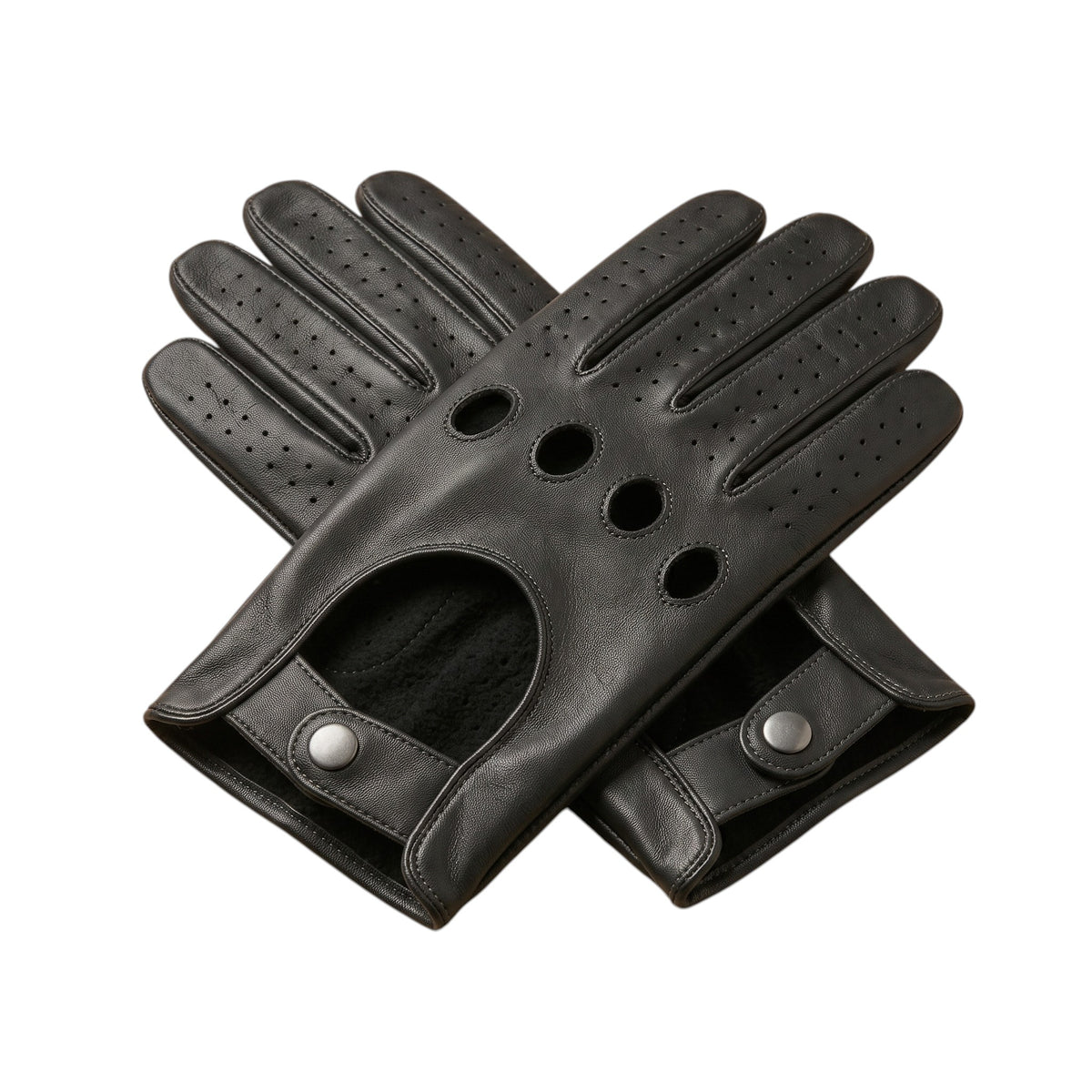 "A pair of black leather driving gloves crossed in an X shape, each showing four circular ventilation holes, perforated fingers, and snap-button wrist straps on a white background.