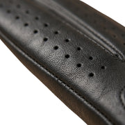 "Extreme close-up of a black leather driving glove's finger area, showing small ventilation perforations and stitching against a white background."