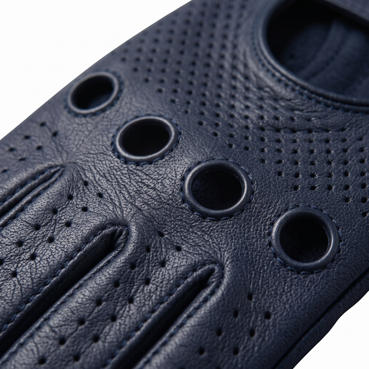 **"Close-up of navy leather driving glove's knuckle vent holes and perforations"**