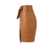 "Side view of brown faux leather mini skirt showing front tie bow belt, front zipper detail with slit, and fitted silhouette – women's fashion product photo on white background."