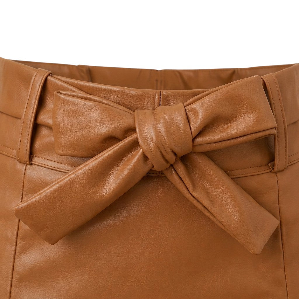 "Close-up detail of tied bow belt on brown faux leather mini skirt waistband, showing knot, belt loops, and leather texture."
