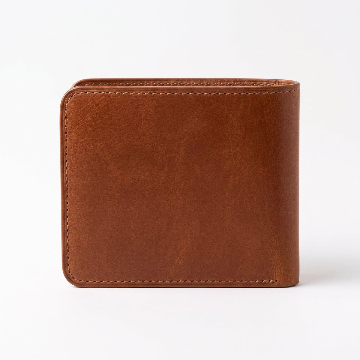 "Brown tan leather bifold wallet standing upright, viewed straight-on from the front, showing rich natural leather grain with tonal variation, rounded corners, and contrasting cream stitching along the top and bottom edges, photographed against a plain white background with a soft shadow beneath."