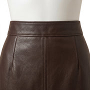 "Close-up of the front waistband on a dark brown leather pencil skirt, showing the stitching, center seam, and leather grain texture."