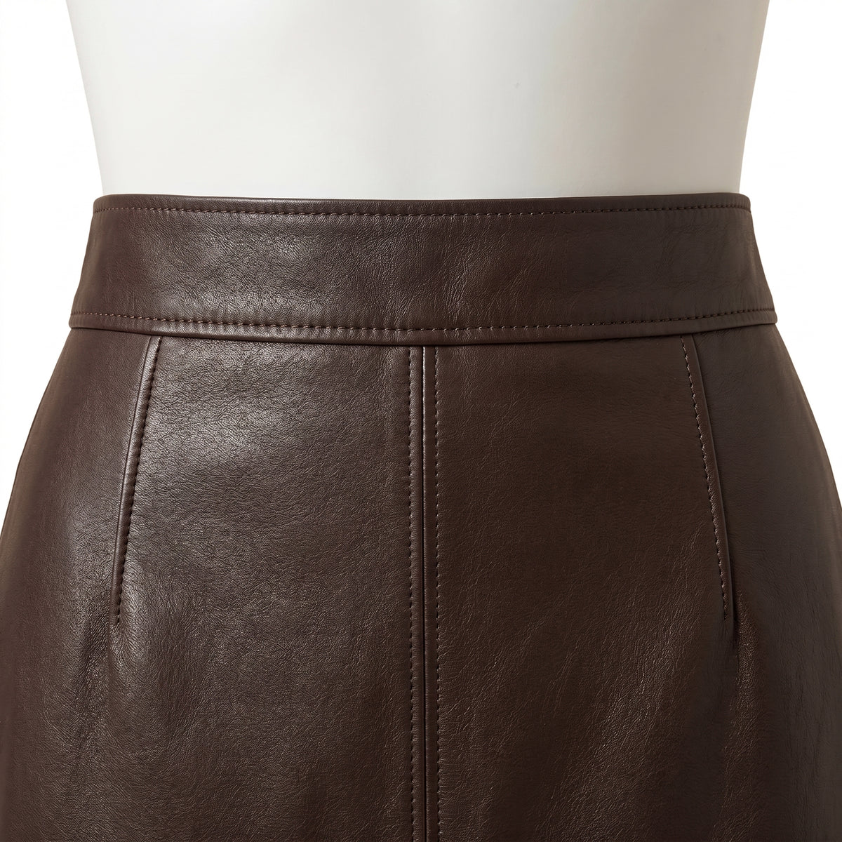 "Close-up of the front waistband on a dark brown leather pencil skirt, showing the stitching, center seam, and leather grain texture."