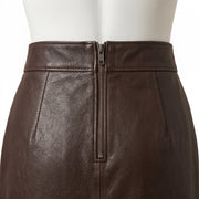 "Close-up of the back zipper on a dark brown leather pencil skirt, showing the waistband stitching and leather grain texture."