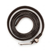 "Overhead view of a thin brown and white cow-print leather belt tightly coiled into a spiral, with a silver-tone buckle at the bottom, photographed on a white background."