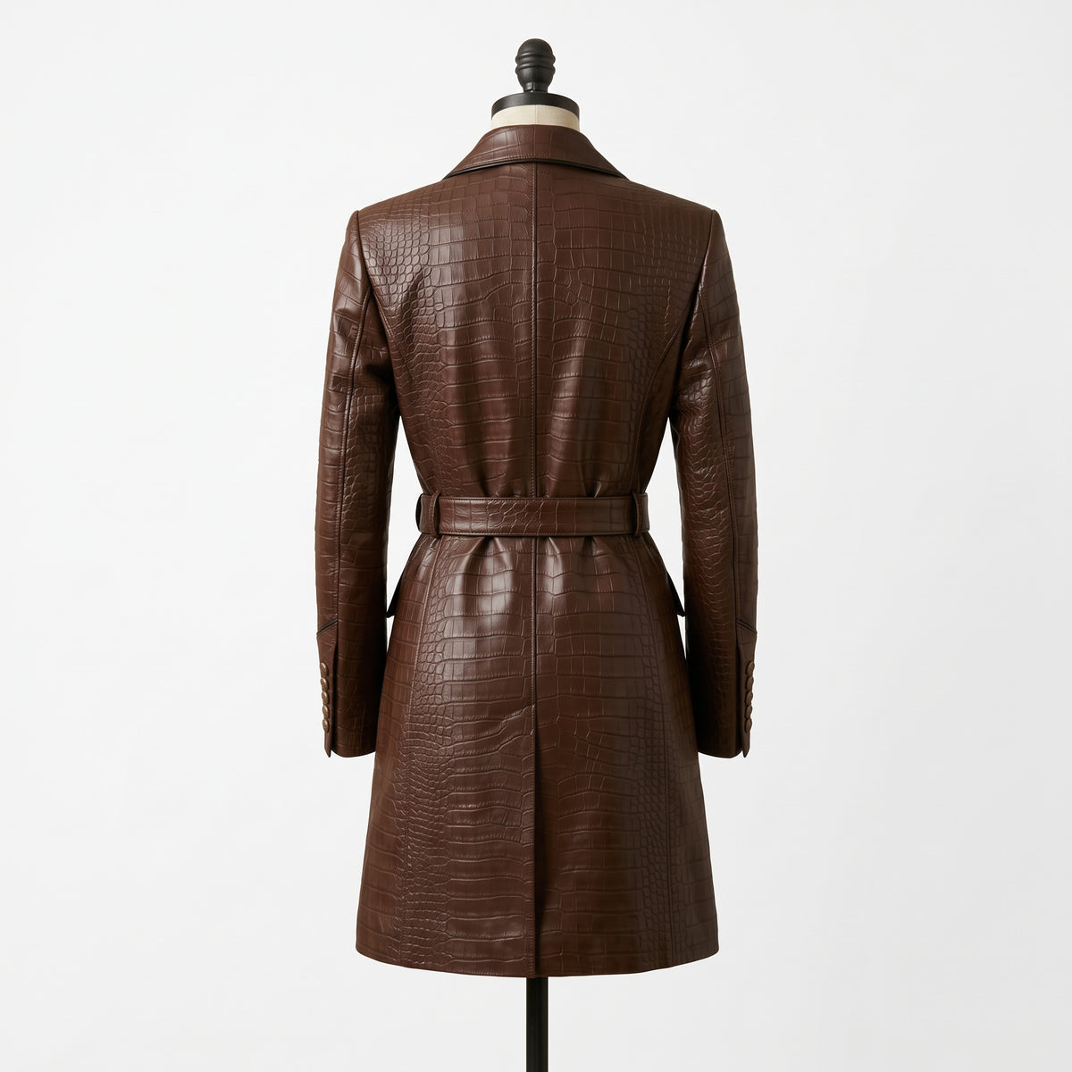 "Back view of a brown crocodile-embossed leather coat with notch lapel, belted waist, and back vent, displayed on a mannequin against a white background."