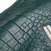 **"Close-up texture of green crocodile-embossed leather jacket pocket"**
