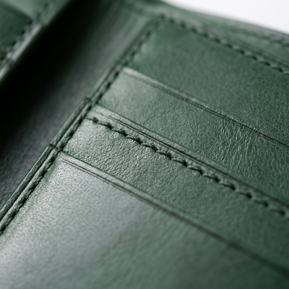 Close-up of a dark green leather wallet showing the interior card slots and fine stitching details.