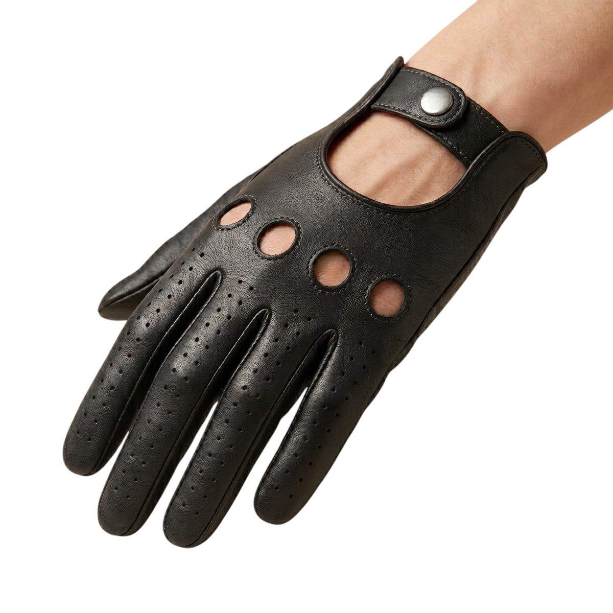 "A hand wearing a black leather driving glove with four circular ventilation holes on the knuckle area, perforated fingers, and a snap-button wrist strap, photographed on a white background."