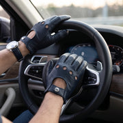 **"Man's hands wearing navy leather driving gloves on car steering wheel"**