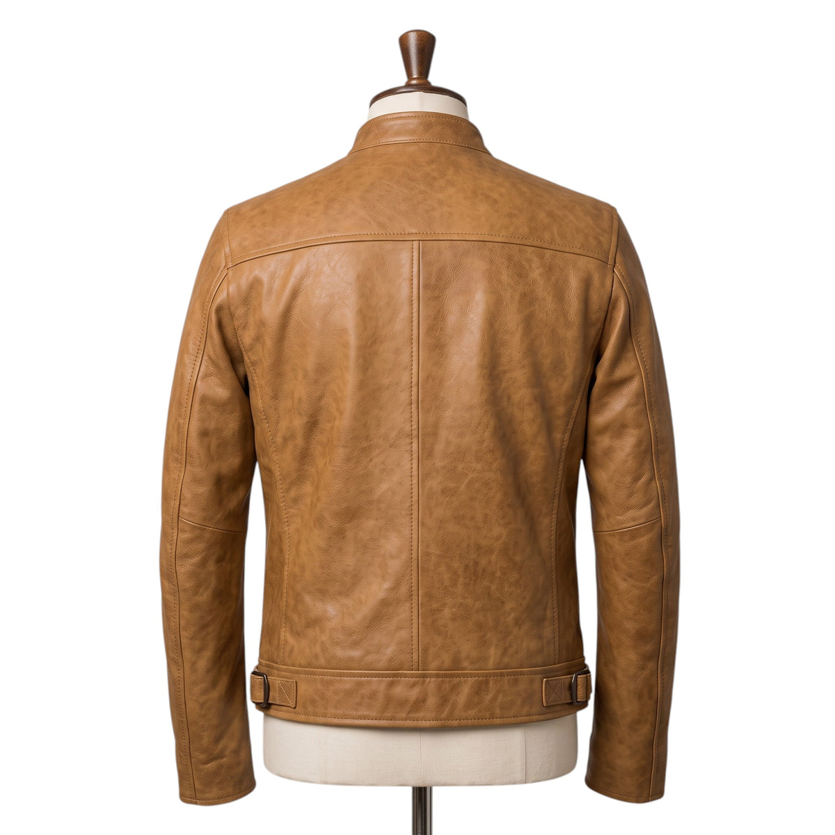 "Back view of a tan leather biker jacket on a mannequin, showing the band collar, back panel seaming, and adjustable buckle tabs at the waist."