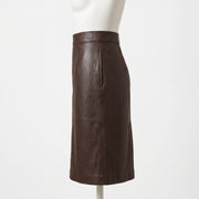 "Side profile view of the dark brown leather pencil skirt on a mannequin, showing the waistband, front seam, and clean silhouette against a light background."