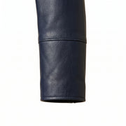 "Close-up detail of a navy blue leather coat's sleeve and cuff seam, showing the smooth grain texture."
