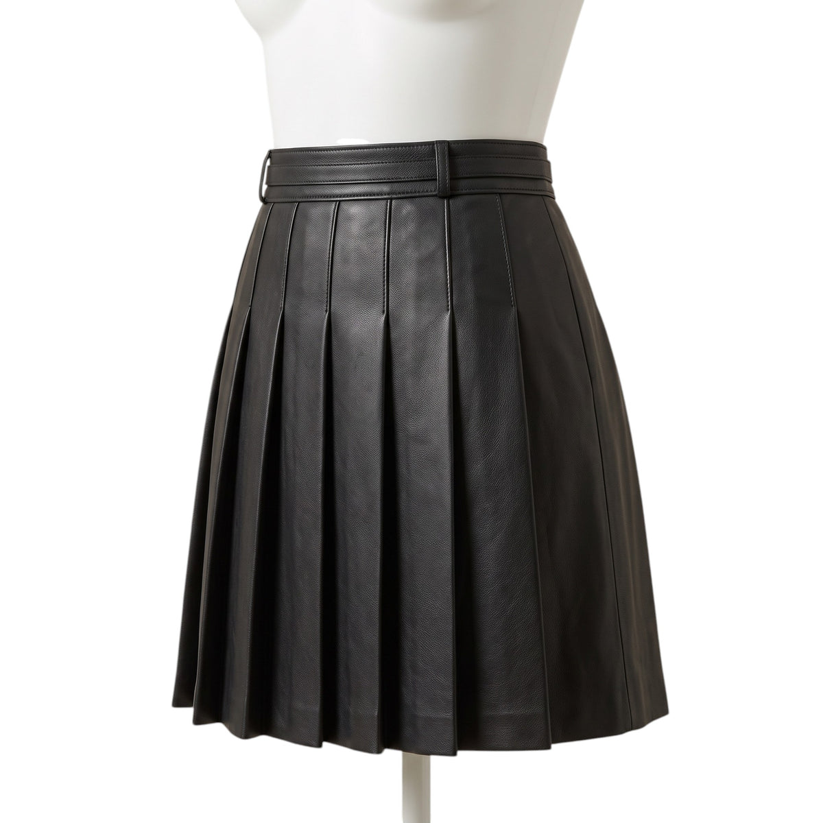 "Slightly angled front view of the black leather pleated mini skirt on a mannequin, showing a belt loop, waistband, and box pleats against a white background."