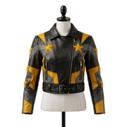 "Front view of a black leather biker jacket with yellow and gray star graphic panels, asymmetric zipper, zip pockets, and belted waist, displayed on a mannequin against a white background."