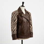 A brown leather and zebra-print jacket displayed on a cream mannequin torso against a plain white background.