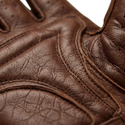 Close-up of a brown leather glove showing detailed stitching, textured grain, and curved paneling against a white background.