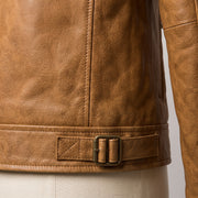 "Close-up of the back waist buckle strap on a tan leather biker jacket, showing a double-prong bronze buckle and diamond-stitched tab detail."