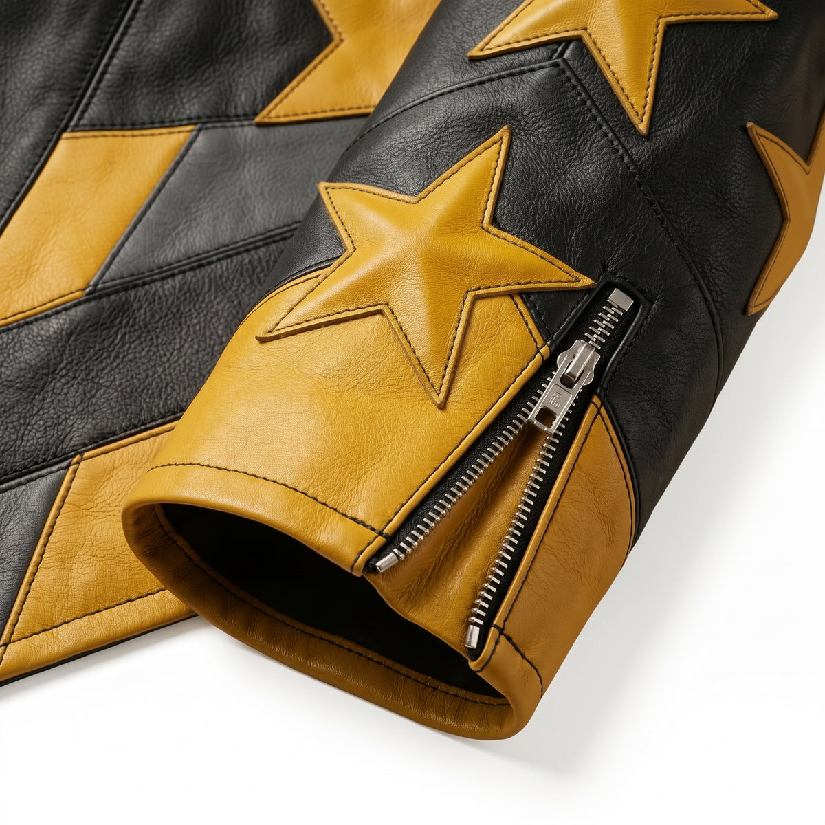 "Close-up detail of a black leather jacket sleeve cuff with yellow star graphic panels and zipper closure."