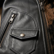 "Extreme close-up of black leather jacket texture showing zip pocket, snap-flap pocket, front zipper, and glimpse of animal-print fur trim."