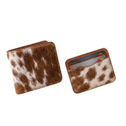 "Angled view of a closed cow-print (brown and white) leather bifold wallet on the left and a matching card holder with credit cards inside on the right, both photographed on a white background."
