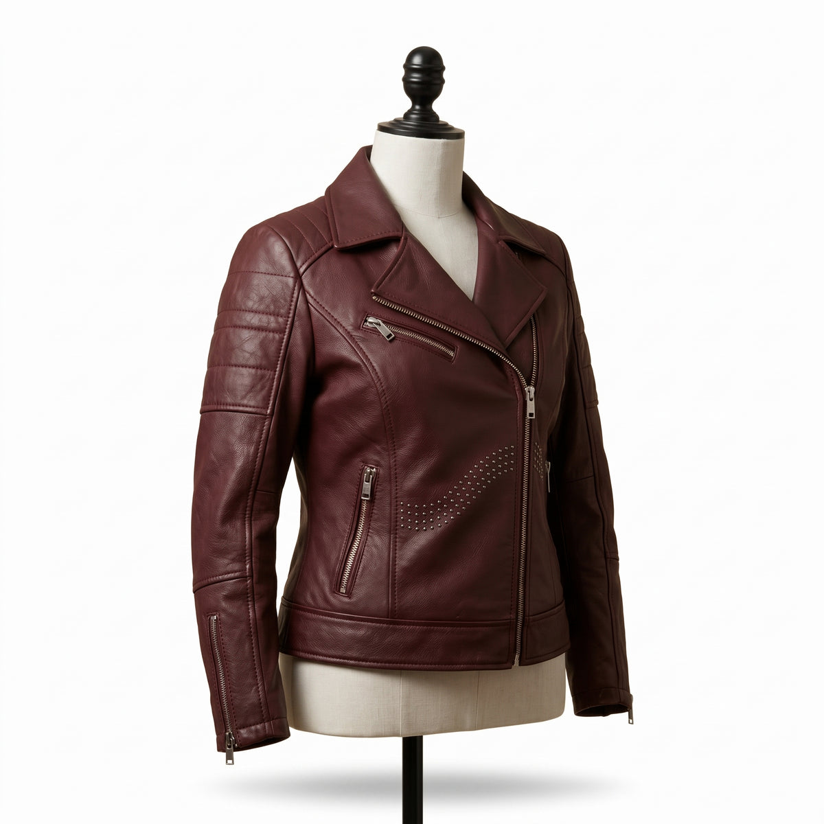 "Angled view of a maroon leather biker jacket with asymmetric front zipper, notch lapel, multiple zip pockets, and stud detailing, displayed on a mannequin against a white background."