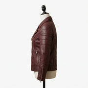 "Full profile side view of a maroon leather biker jacket with notch lapel, zip pockets, and stud detailing, displayed on a mannequin against a white background."