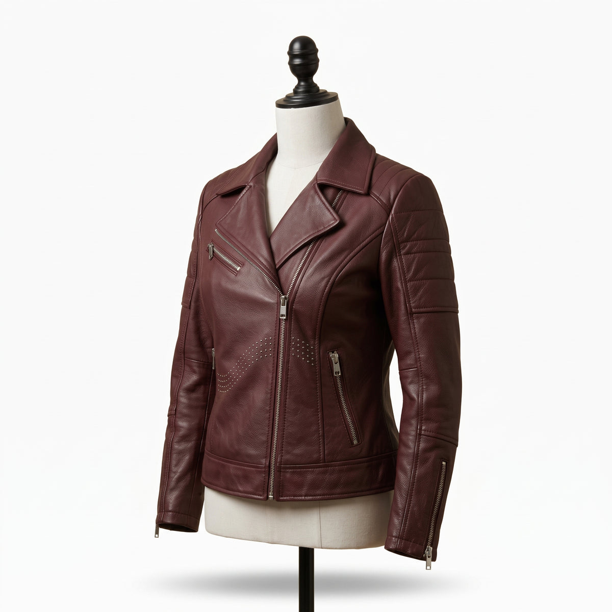 "Angled view of a maroon leather biker jacket with asymmetric front zipper, notch lapel, multiple zip pockets, and stud detailing, displayed on a mannequin against a white background."