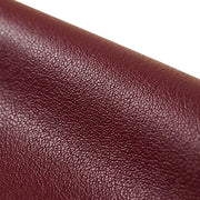 "Extreme close-up macro shot of maroon faux leather grain texture, showing fine pebbled surface detail against a white background."
